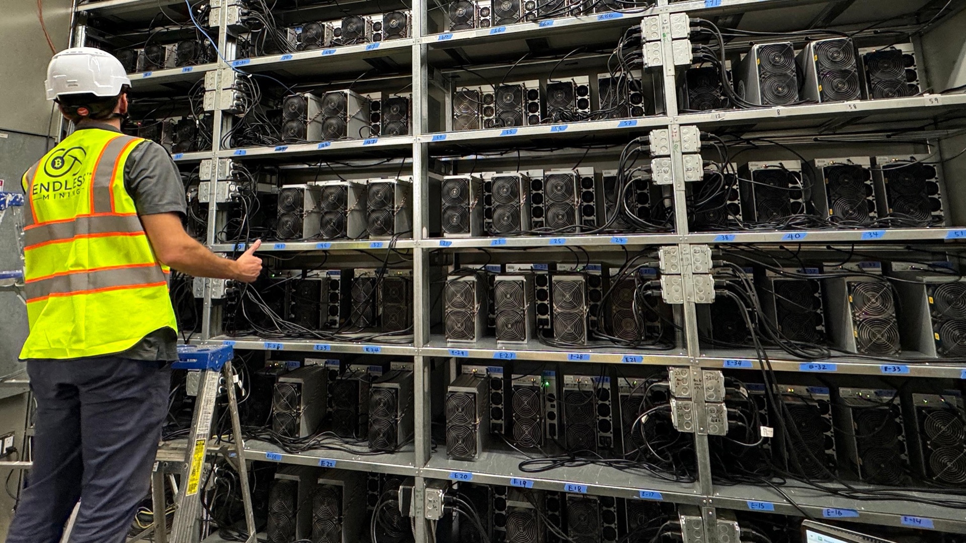 An Endless Mining technician checking racks of hosted ASIC miners at our facility