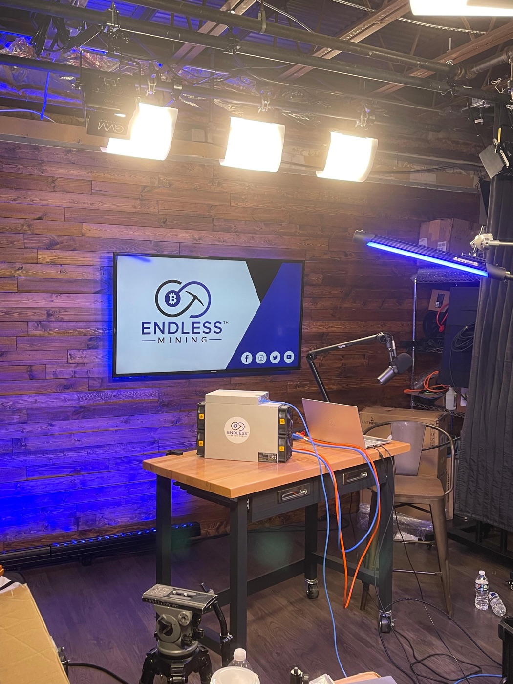 The Endless Mining studio, with a miner on the bench and the company logo on screen